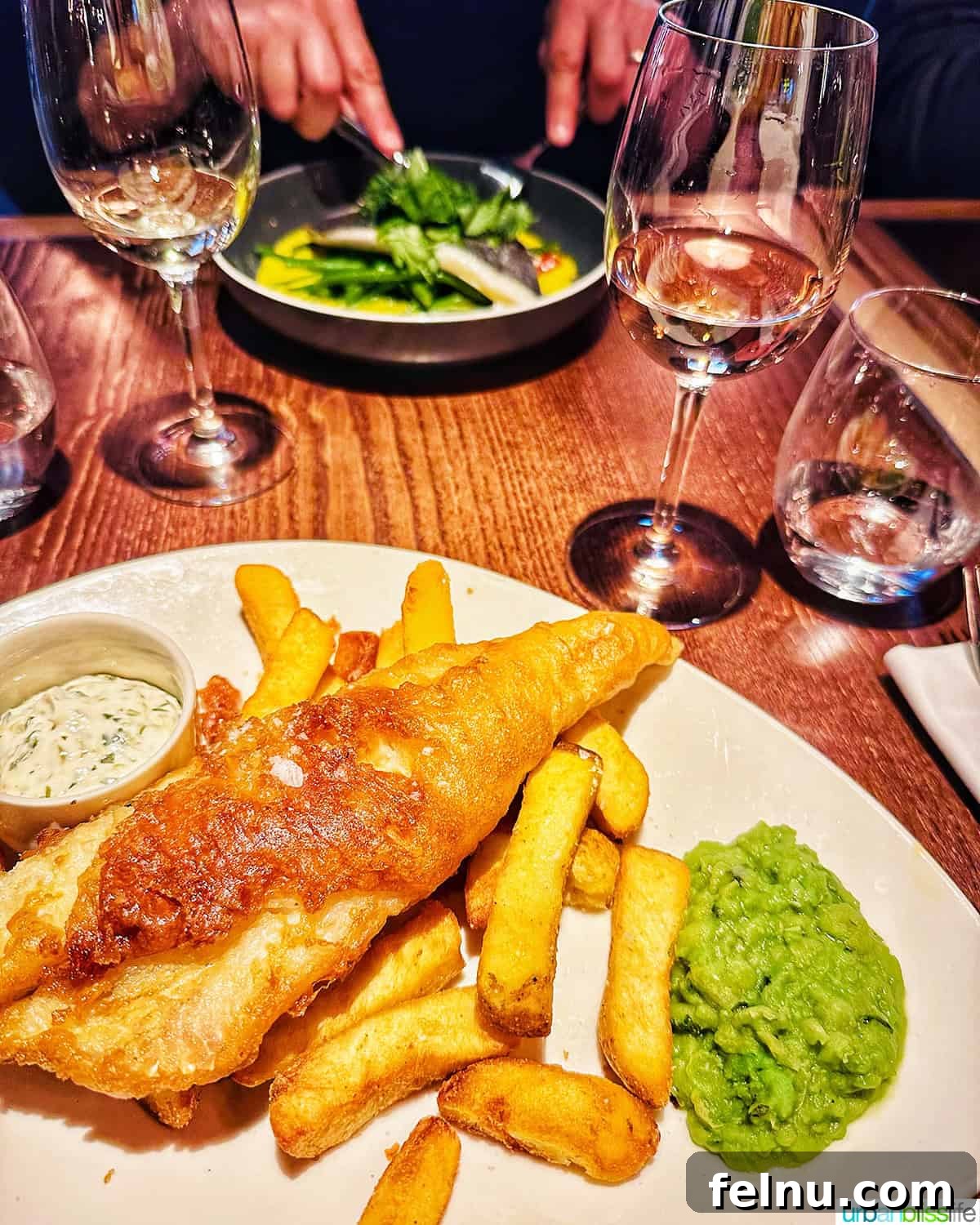 London's Culinary Gems 2 Crispy fish and chips, a quintessential British meal, served with mushy peas and tartar sauce, at Heddon Street Kitchen in London.