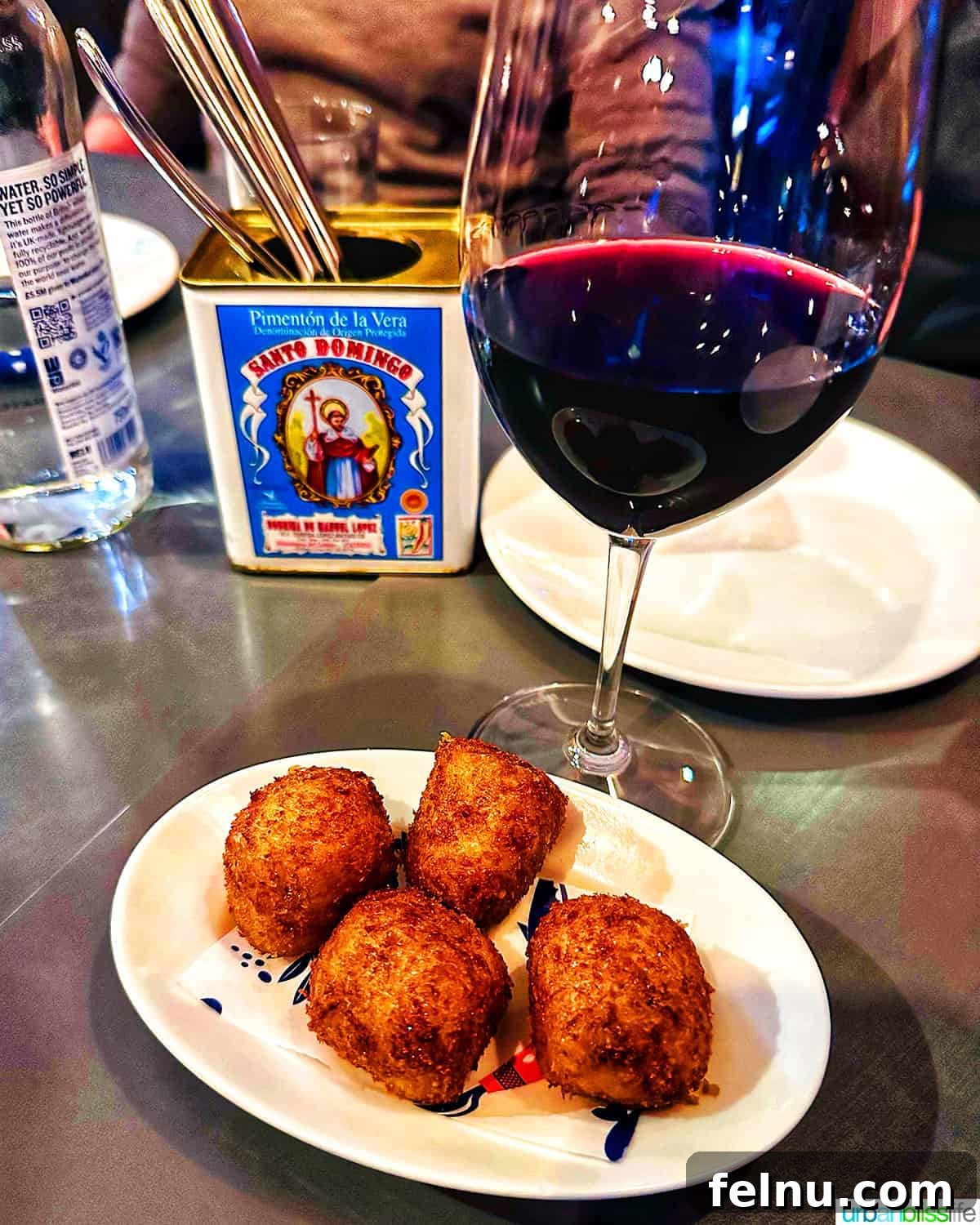 London's Culinary Gems 11 A glass of vibrant red wine perfectly paired with a plate of crispy ham croquetas, a classic Spanish tapa, at Brindisa in London.