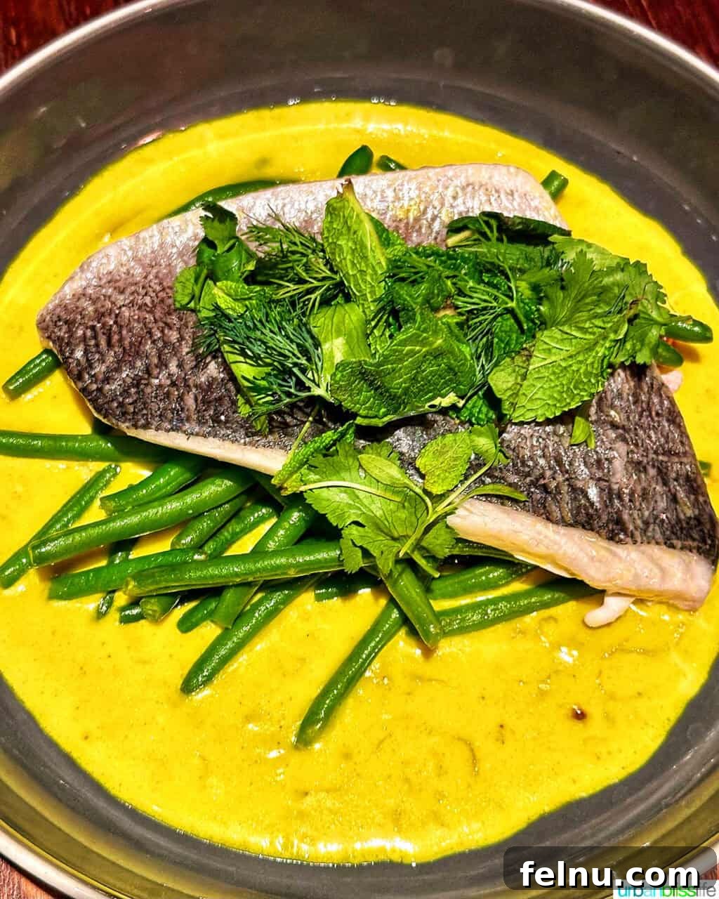 London's Culinary Gems 19 A beautifully plated roasted sea bream dish, served with green beans and a golden, curry-like sauce, at Gordon Ramsay's Heddon Street Kitchen in London.