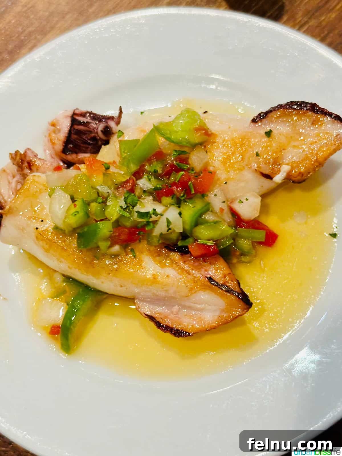 12 Essential Pintxos to Taste 11 Grilled squid (calamares) served as a pintxo with colorful chopped peppers, showcasing fresh seafood.