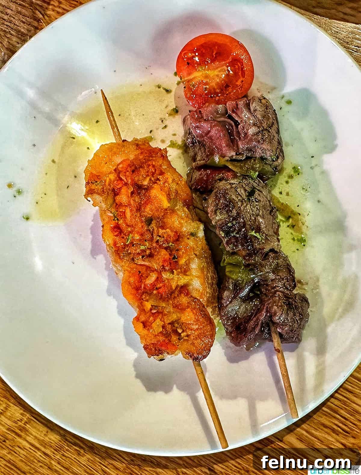 12 Essential Pintxos to Taste 4 A gourmet plate featuring two distinct pintxos: one with succulent grilled steak and another with fresh shrimp, showcasing modern culinary artistry.