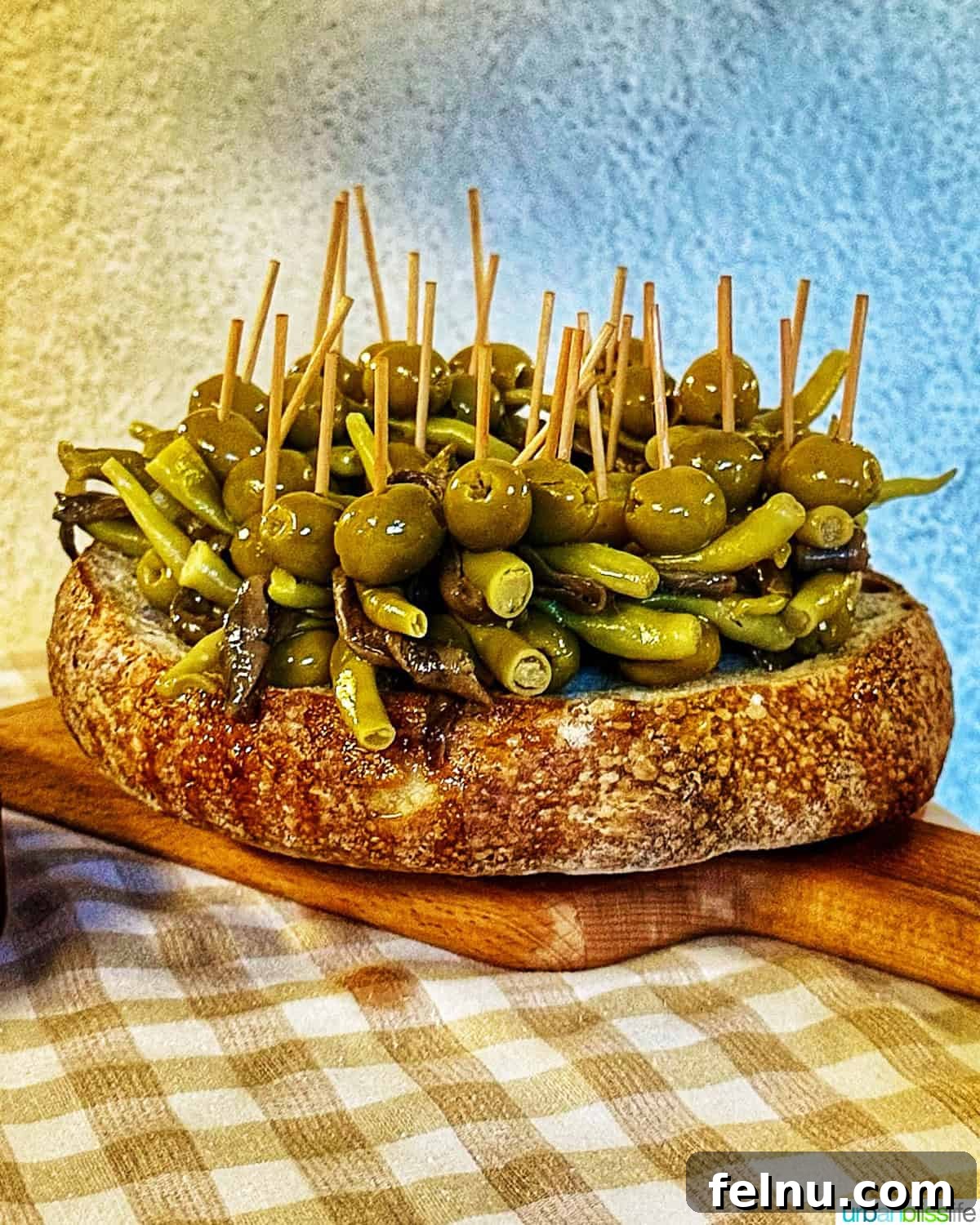 12 Essential Pintxos to Taste 5 A close-up of a traditional Gilda pintxo, featuring skewered green olives, anchovies, and pickled green peppers, displayed in a rustic bread bowl.