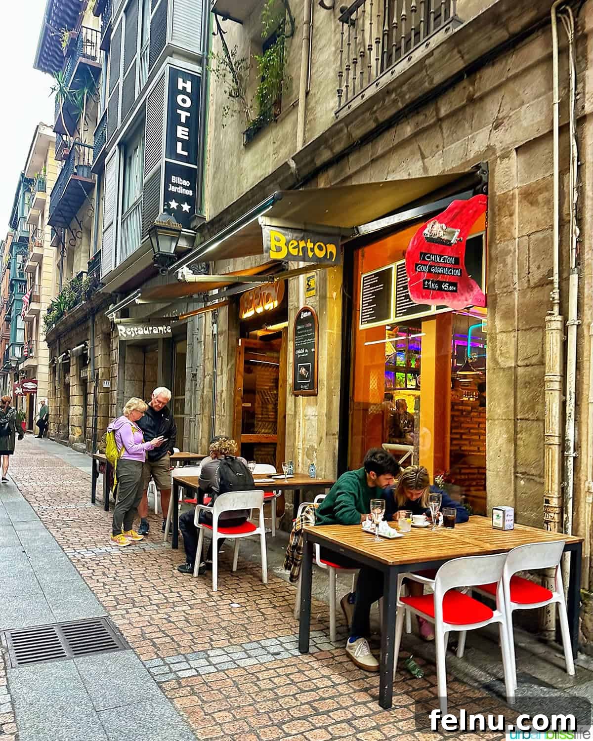The Ultimate Pintxo Crawl: Bilbao's Best Bites 5 An inviting street scene showcasing the exterior of Berton pintxos bar in Bilbao, Spain, with tables spilling onto the sidewalk.
