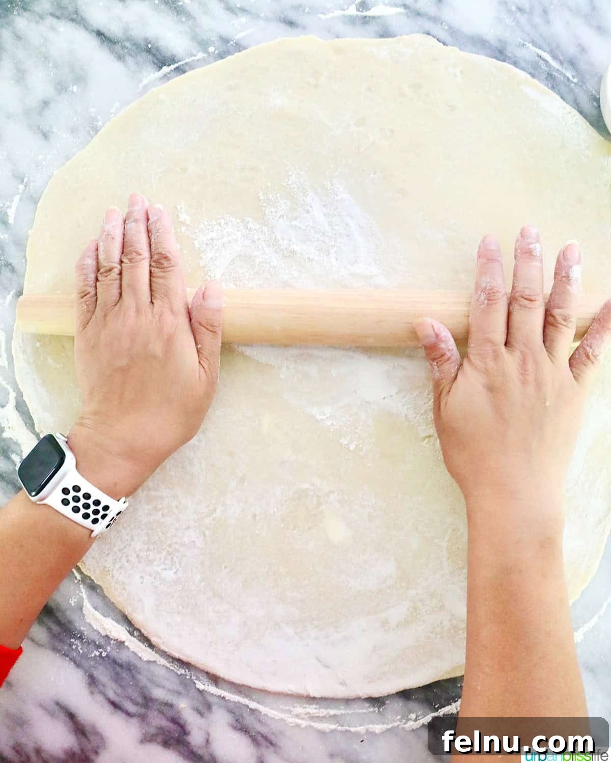 Savory Delights: Recipes Beyond the Sweet 3 Hands using a rolling pin to roll out homemade pie dough on a marble countertop