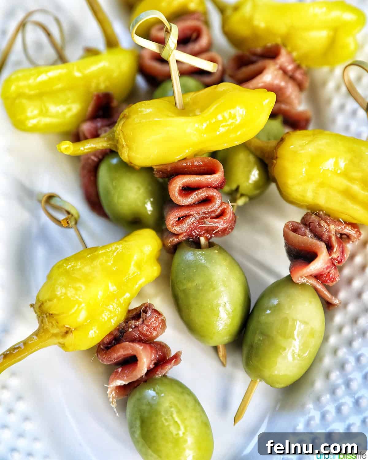 Gilda A Basque Classic 2 Gilda pintxos: food sticks with peppers, anchovies, and olives on a white plate, ready to be served as an easy appetizer.