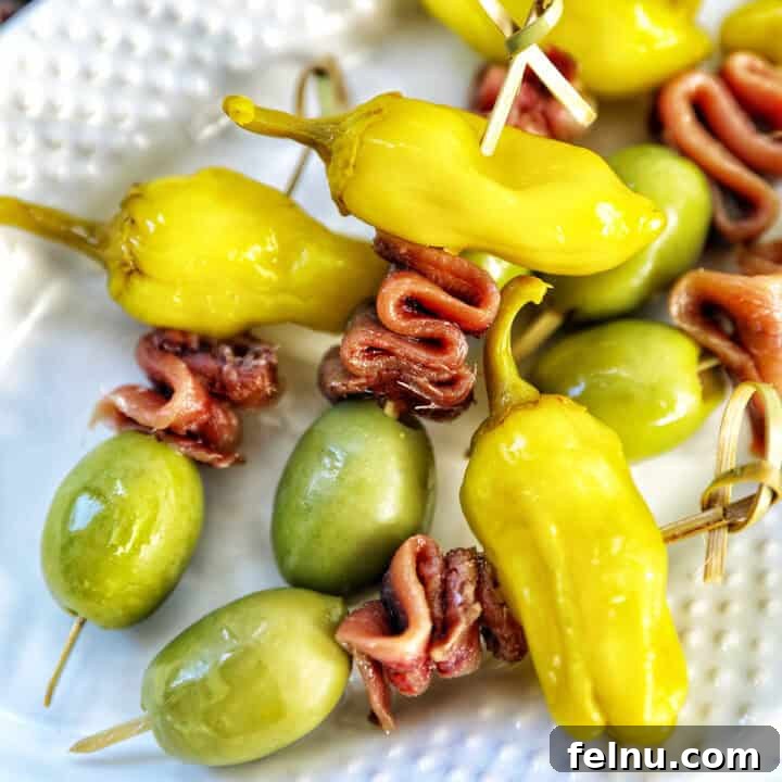 Gilda A Basque Classic 13 Gilda pintxos: food sticks with peppers, anchovies, and olives on a white plate, perfect for parties.