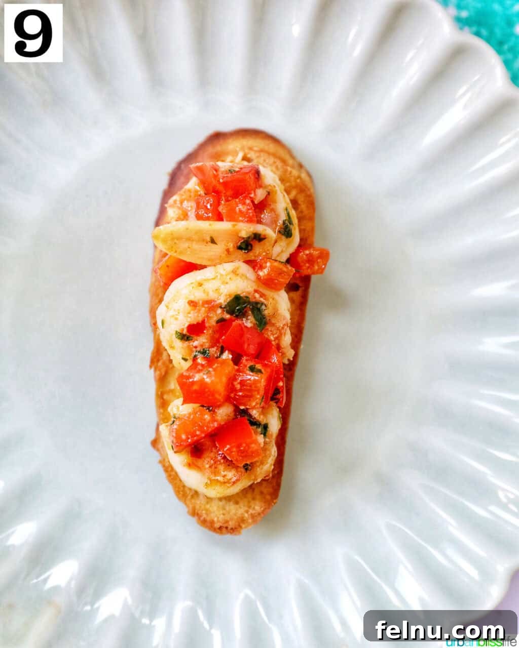 Savory Shrimp Bites 14 shrimp pintxos skewers with tomatoes on crostini bread on a scalloped plate.