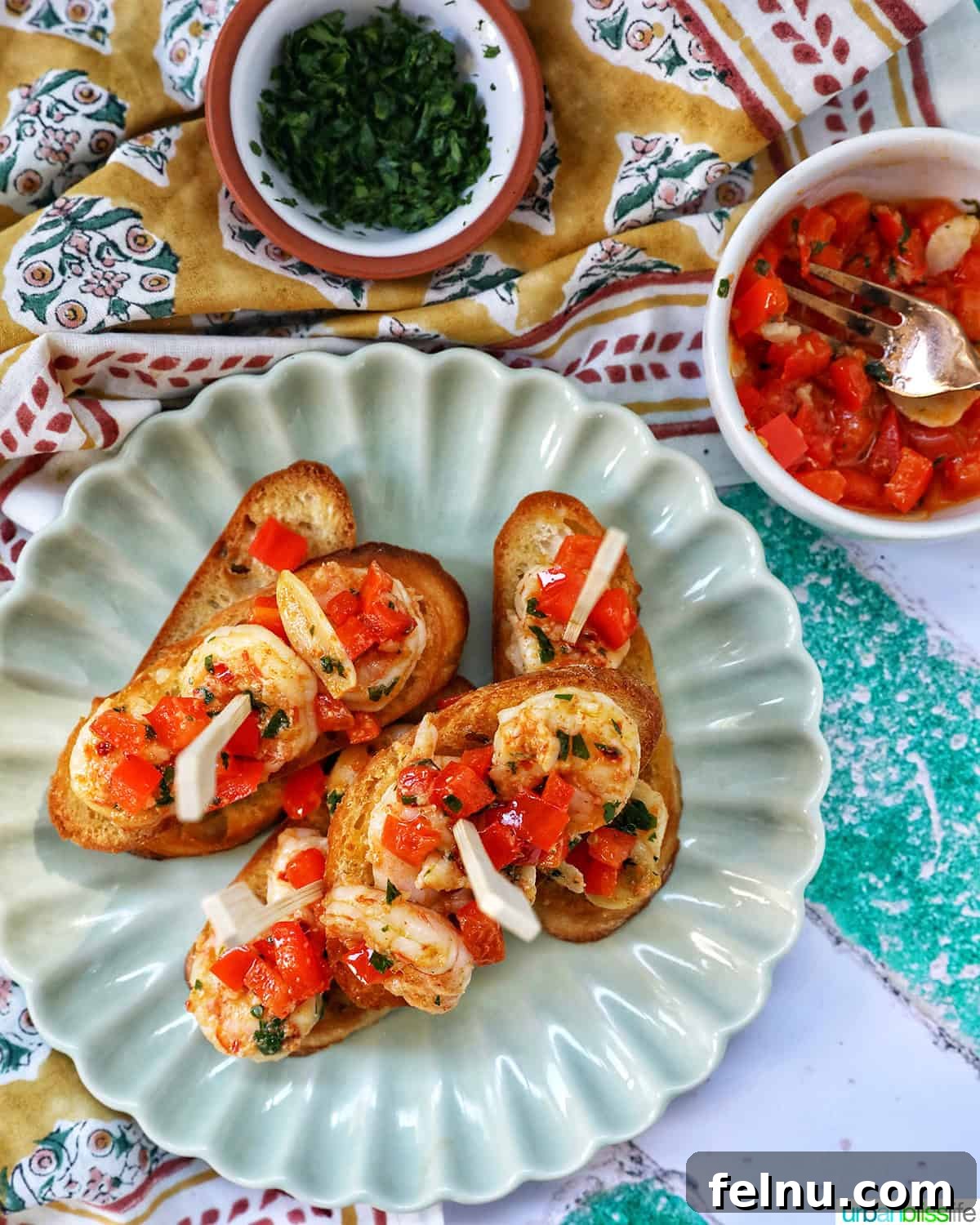 Savory Shrimp Bites 16 shrimp pintxos skewers with tomatoes on crostini bread on a scalloped plate.