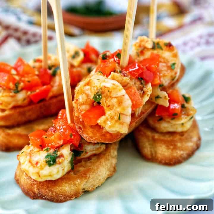 Savory Shrimp Bites 18 shrimp pintxos skewers with tomatoes on crostini bread on a scalloped plate.