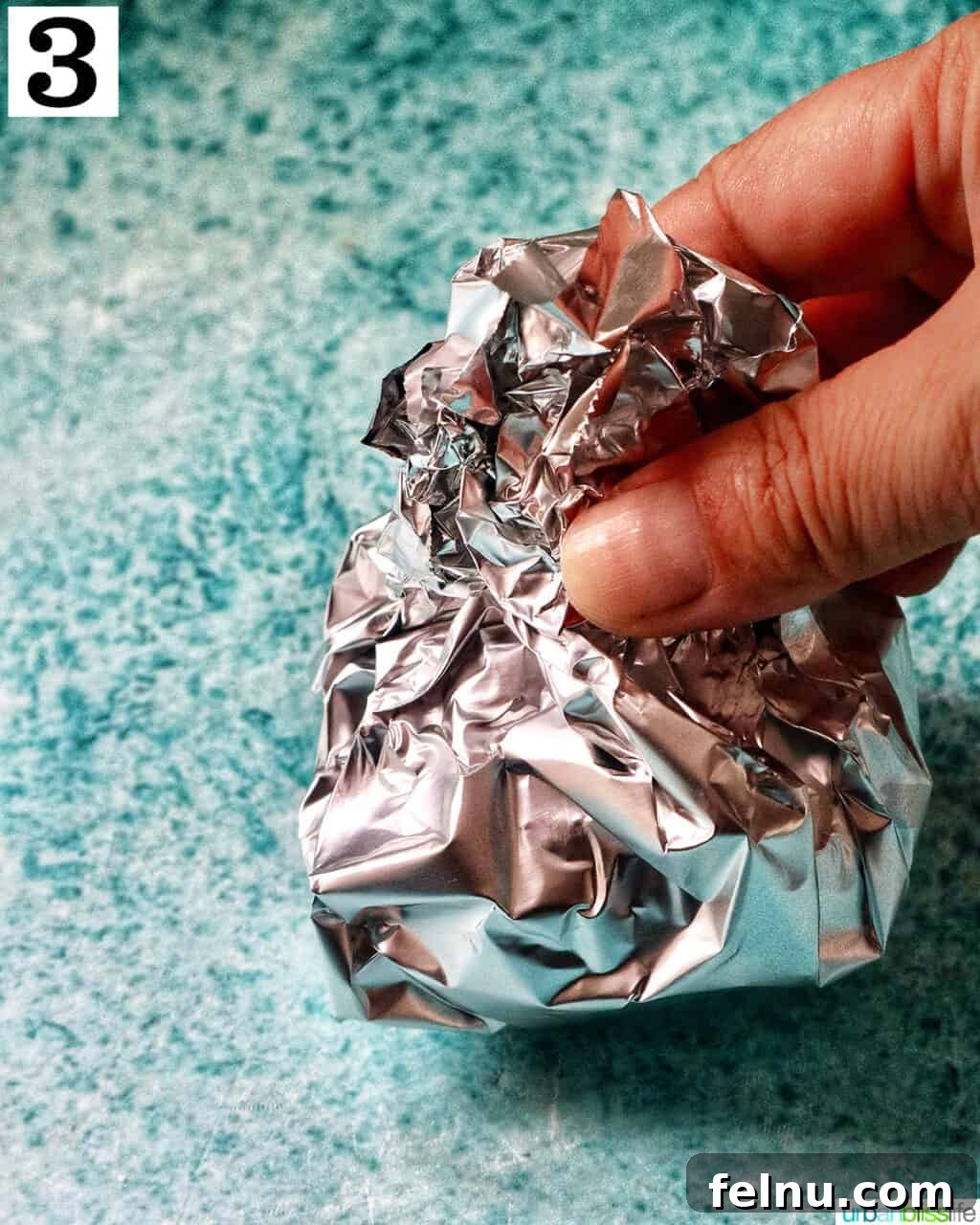 Golden Butternut Squash and Roasted Garlic Spread 7 hand holding aluminum foil pack of garlic head.