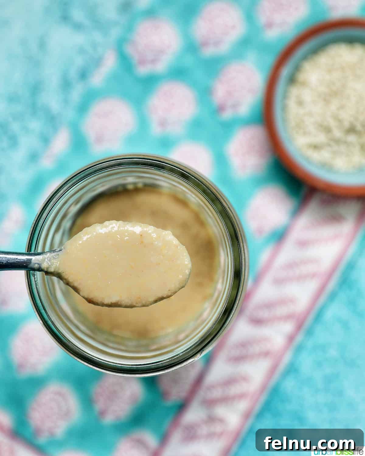 Crafting Your Own Tahini 3 jar of homemade tahini with a small bowl of sesame seeds and a spoon.