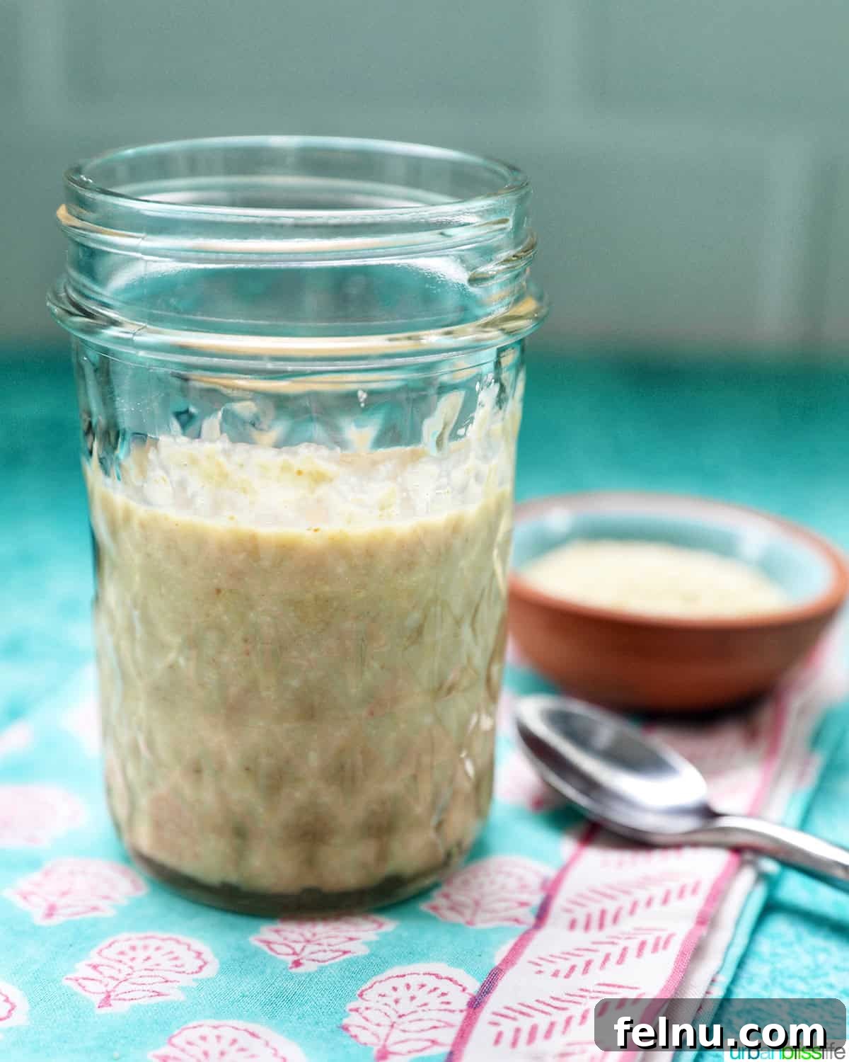 Crafting Your Own Tahini 4 jar of homemade tahini with a small bowl of sesame seeds and a spoon.