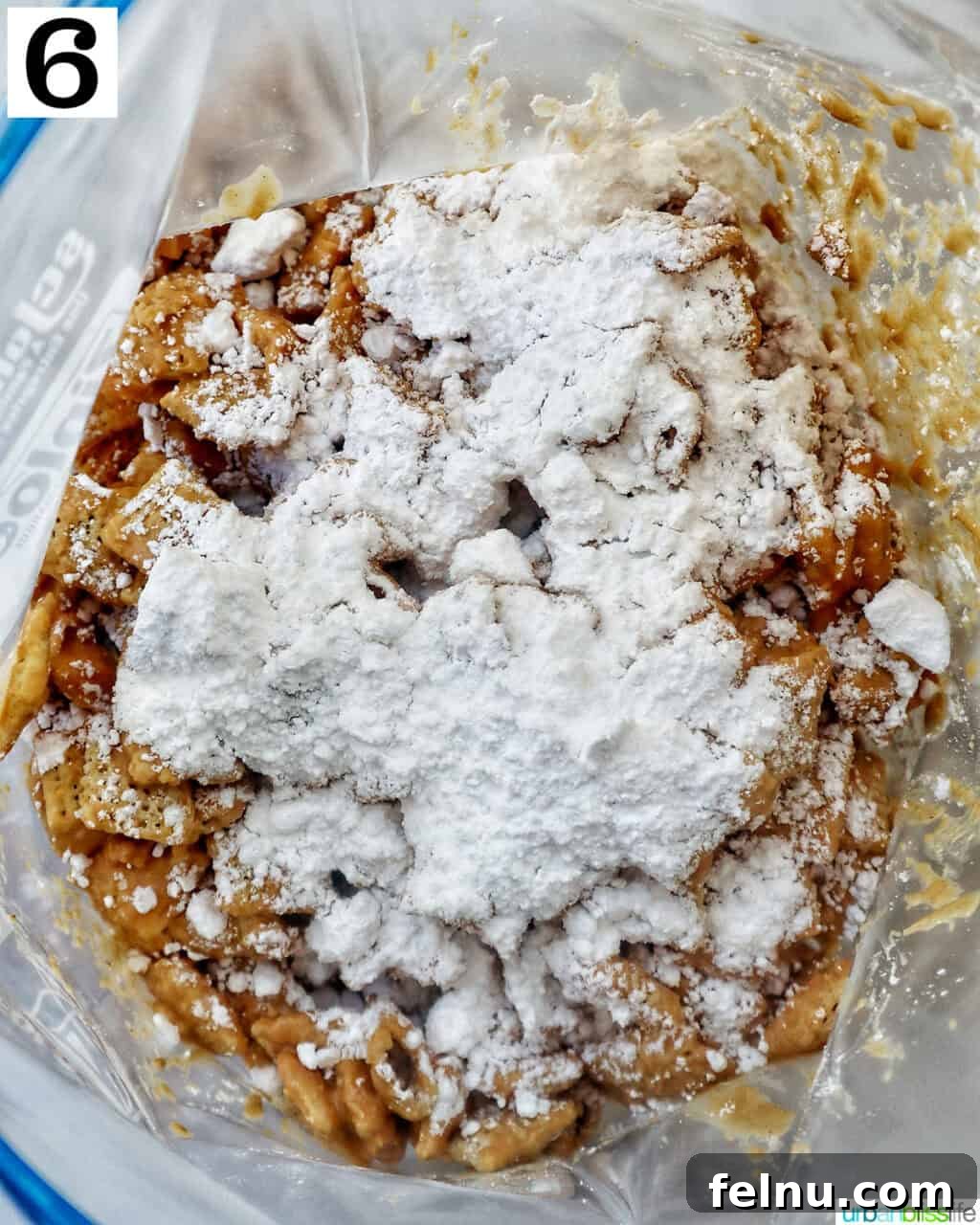 Effortlessly Delicious Patriotic Puppy Chow 12 Adding powdered sugar to patriotic puppy chow in a large plastic bag for coating.