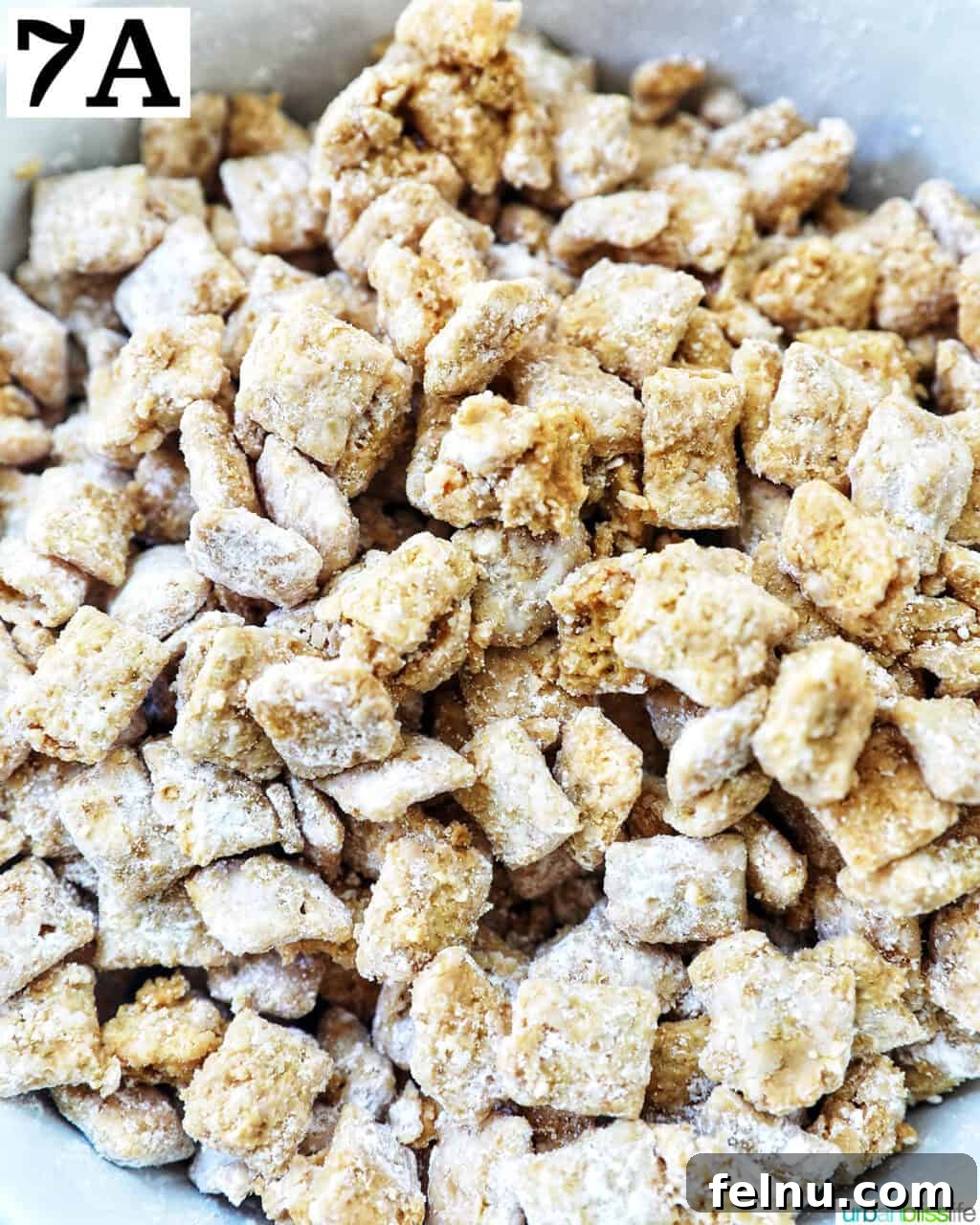 Effortlessly Delicious Patriotic Puppy Chow 13 A close-up of finished puppy chow in a bowl, showing the powdered sugar coating.