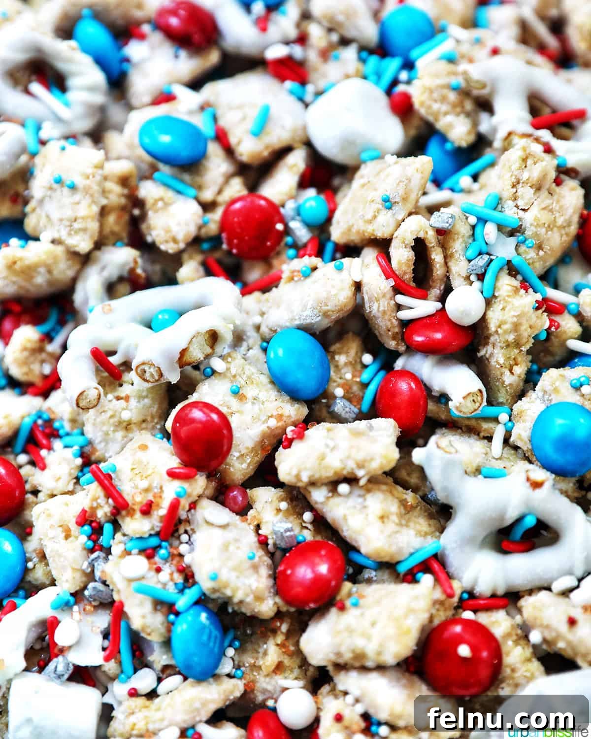 Effortlessly Delicious Patriotic Puppy Chow 15 Close-up of a bowl of red, white, and blue patriotic puppy chow, highlighting the colorful candies and powdered sugar coating.