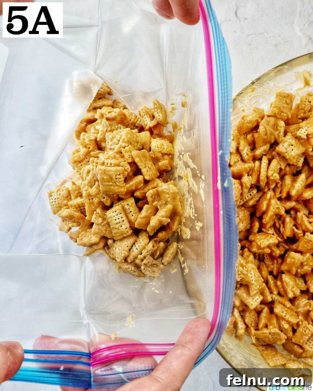Effortlessly Delicious Patriotic Puppy Chow 10 Transferring the coated puppy chow mixture into a large gallon-sized plastic ziplock bag.