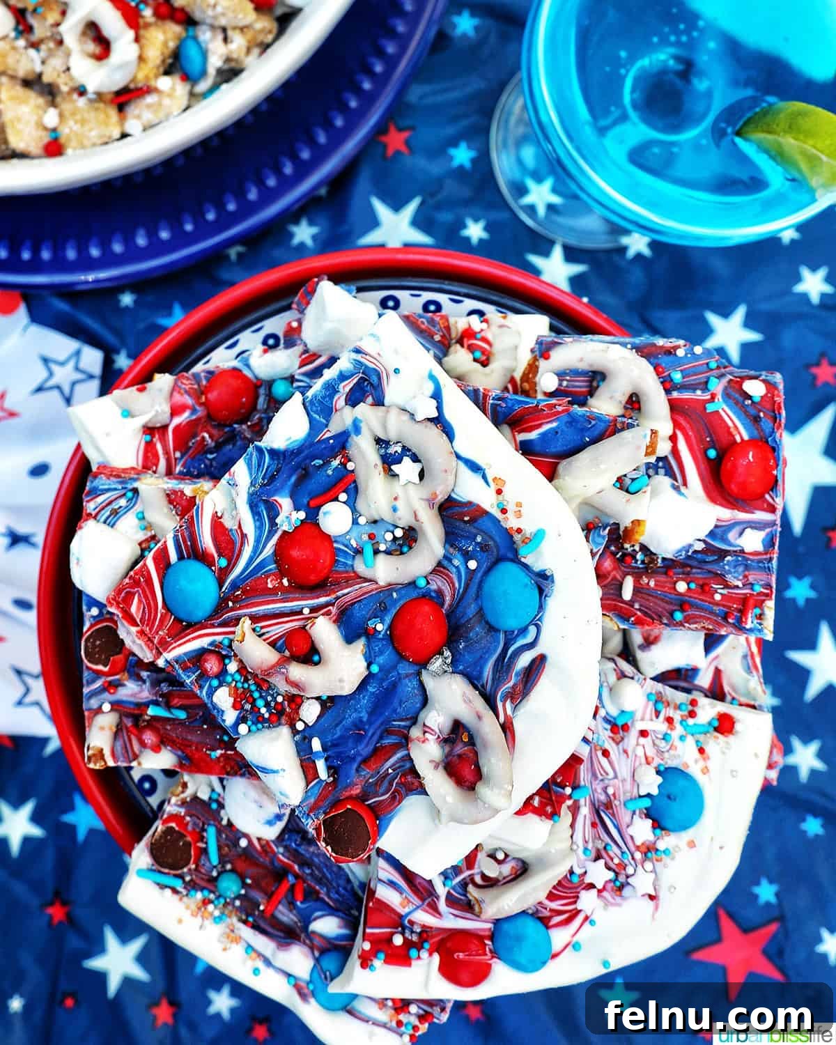 Fourth of July Freedom Bark 15 A bowl stacked with pieces of red, white, and blue bark, presented alongside a vibrant blue cocktail, ready for a festive celebration.