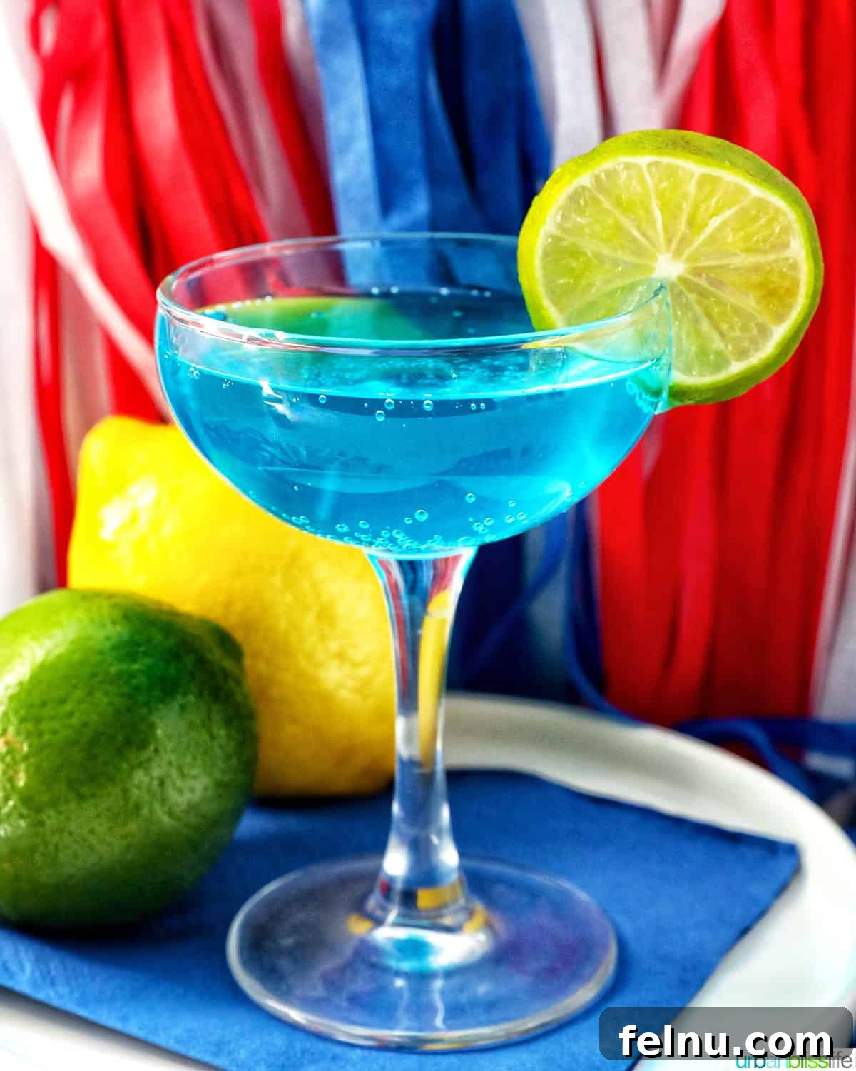 Fourth of July Freedom Bark 17 A vibrant blue wave cocktail garnished with a lime slice, set against a backdrop of red, white, and blue election night decorations.