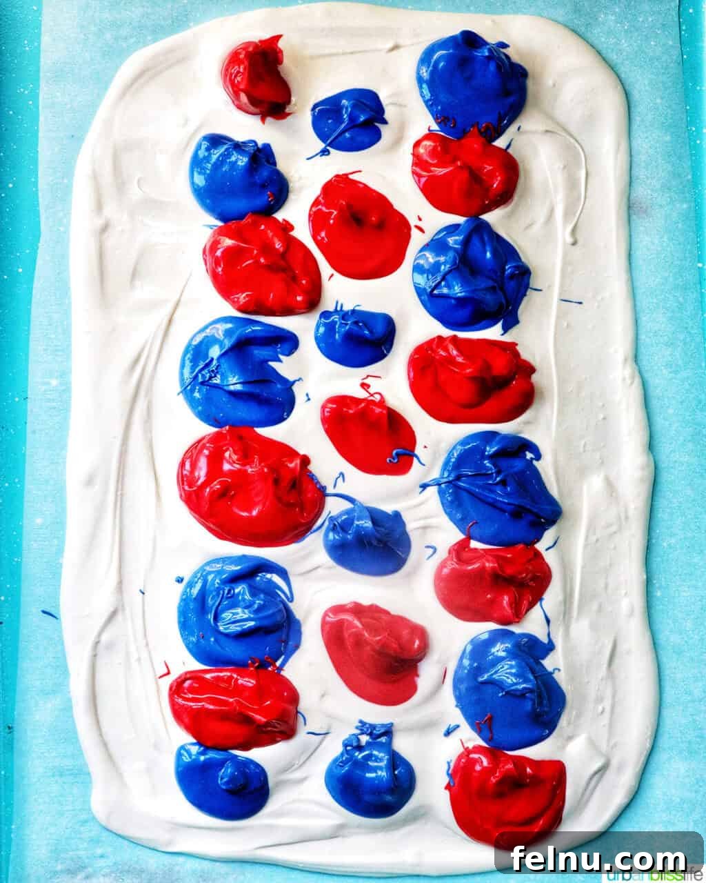 Fourth of July Freedom Bark 8 A vibrant display of red, white, and blue melted chocolate artfully swirled together on a baking sheet, forming a beautiful marbled pattern.
