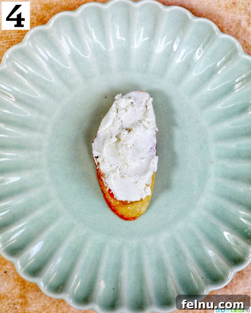 Golden Onion and Chevre Morsels 8 Creamy goat cheese spread evenly over a toasted crostini slice on a green plate.