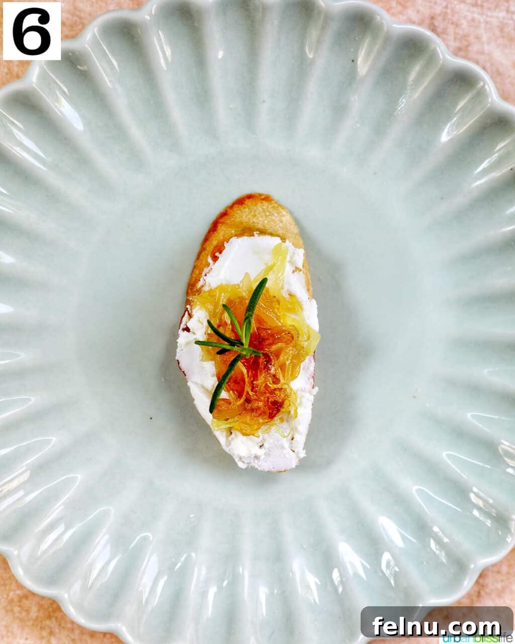 Golden Onion and Chevre Morsels 10 The finished caramelized onion and goat cheese crostini, garnished with fresh rosemary, ready for serving.