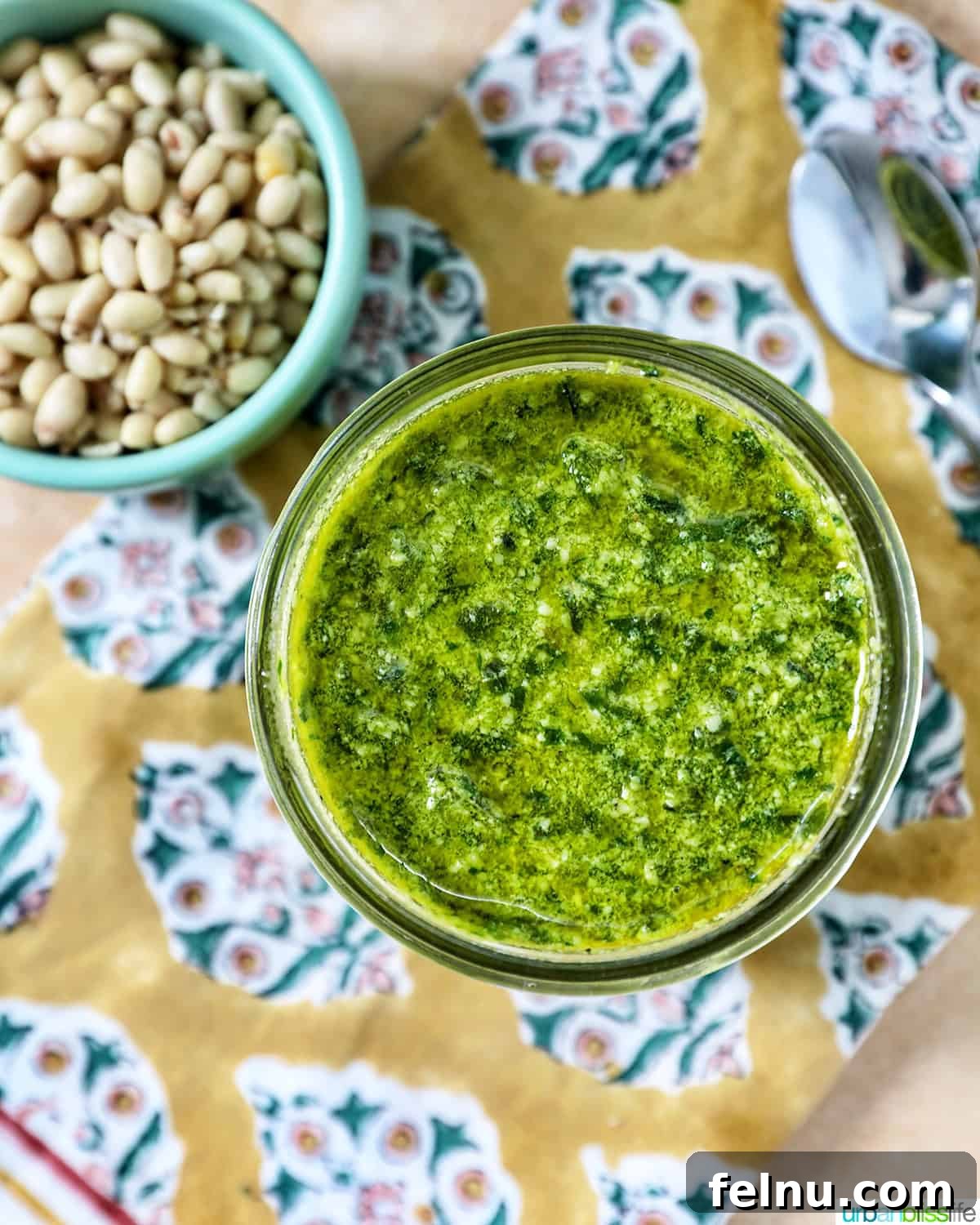 Homemade Basil Pesto: A Burst of Summer Flavor 3 Homemade pesto in a mason jar next to a bowl of pine nuts and fresh basil leaves