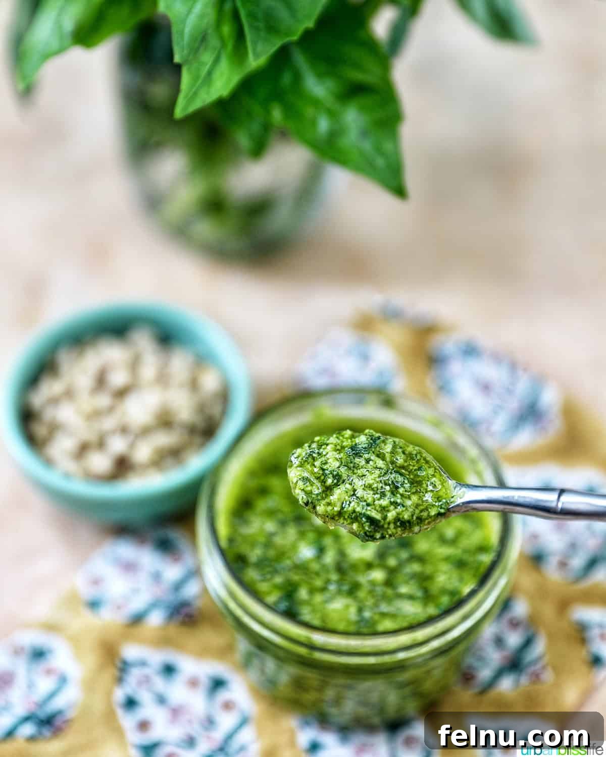 Homemade Basil Pesto: A Burst of Summer Flavor 9 Mason jar with a spoon full of basil pesto next to a bowl of pine nuts