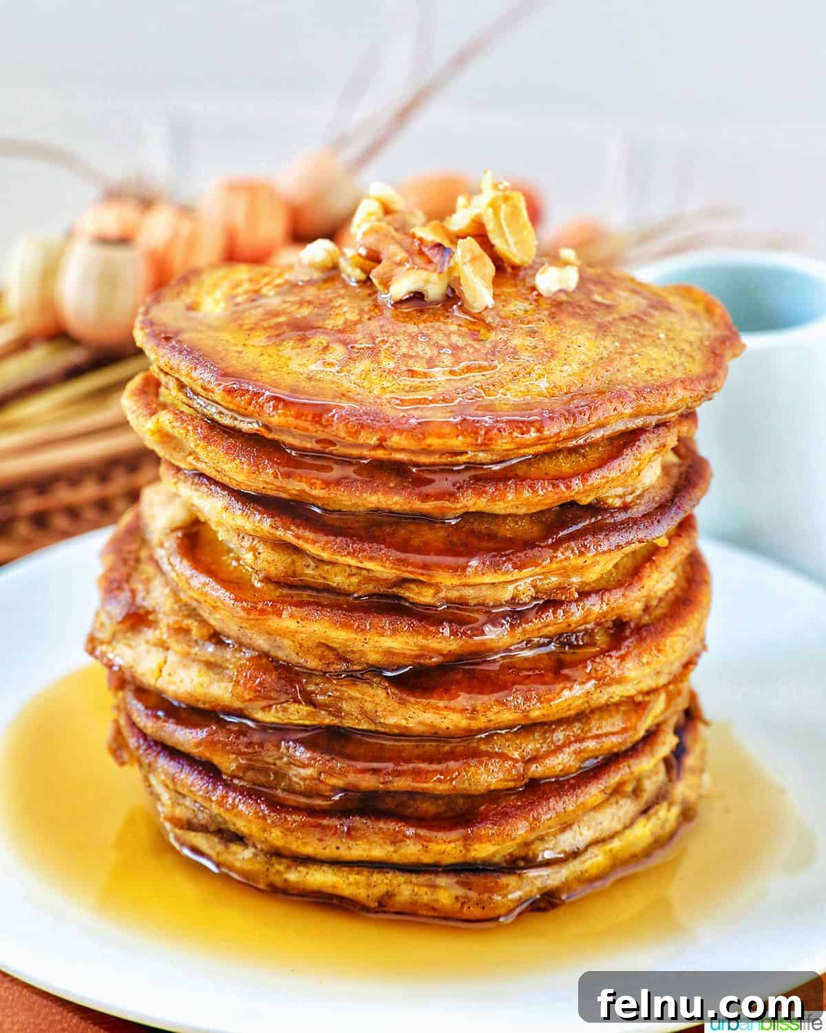 Stack of delicious pumpkin spice pancakes, drizzled with maple syrup and topped with pecans.