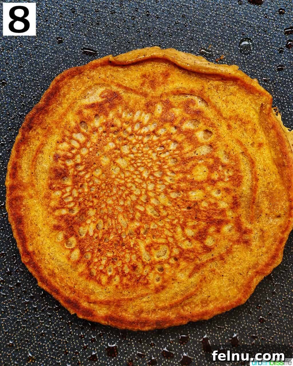 Cooked pumpkin spice pancake on a hot griddle, ready to be flipped.