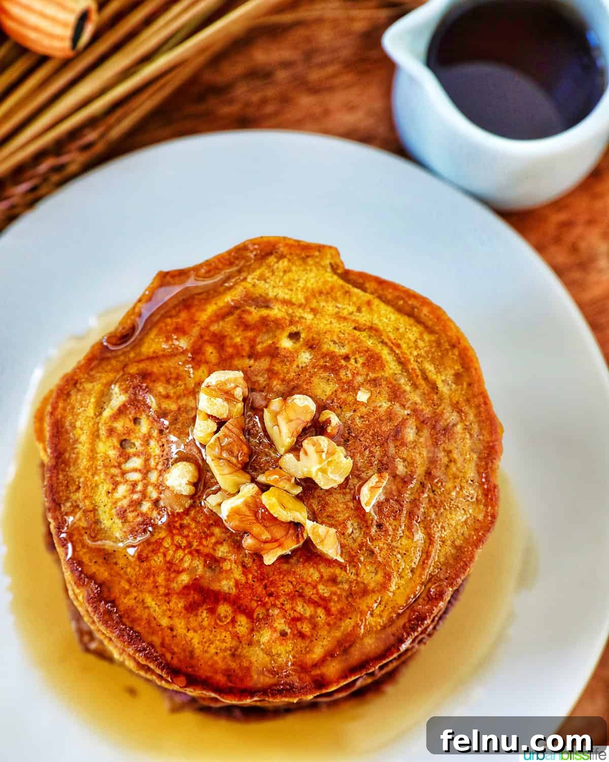 Overhead shot of pumpkin pie spice pancakes with syrup and fall decorations.