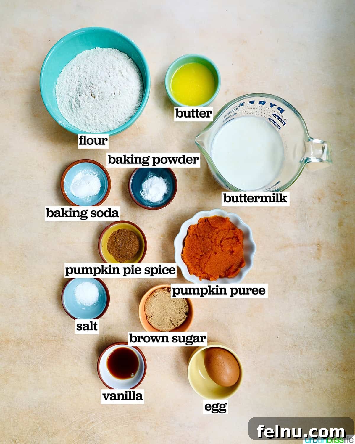Bowls of ingredients for making pumpkin pie spice pancakes, including flour, pumpkin puree, and spices.