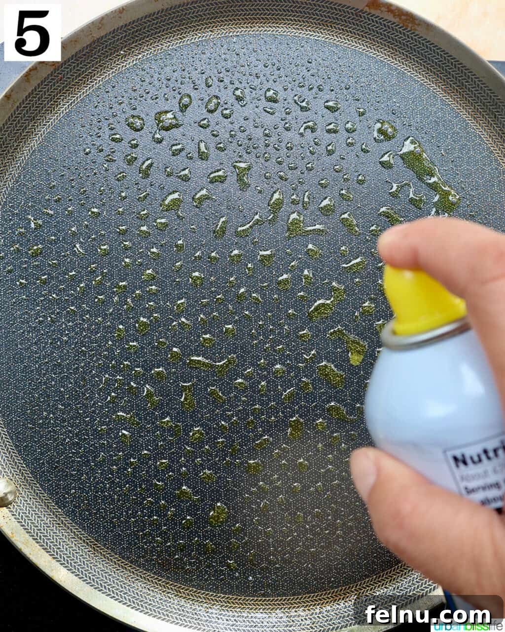 Spraying cooking spray onto a hot griddle.