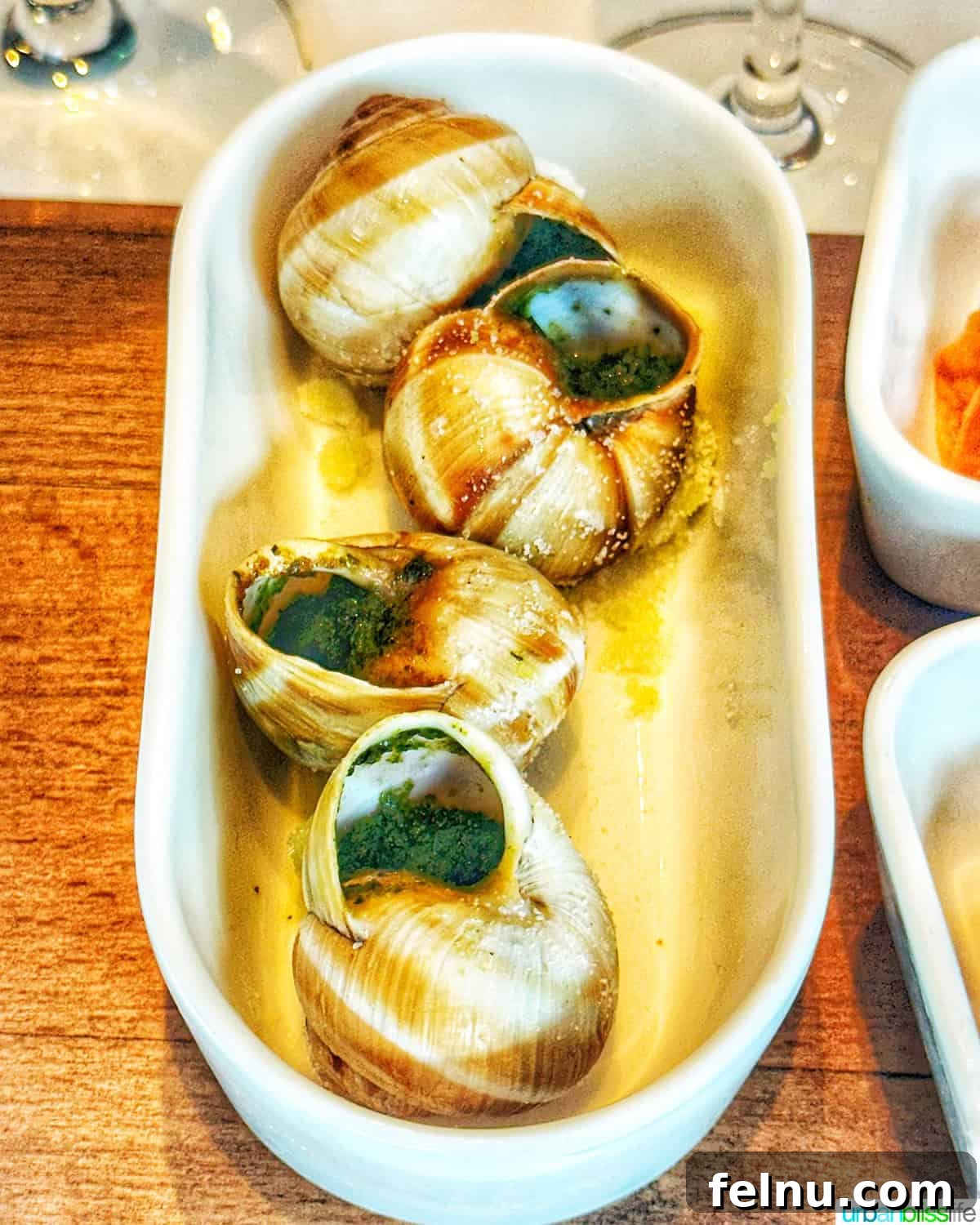 Iconic French Culinary Delights 6 A bowl filled with cooked escargots, presented in their shells, garnished with fresh herbs, hinting at the rich garlic butter they're often served in.