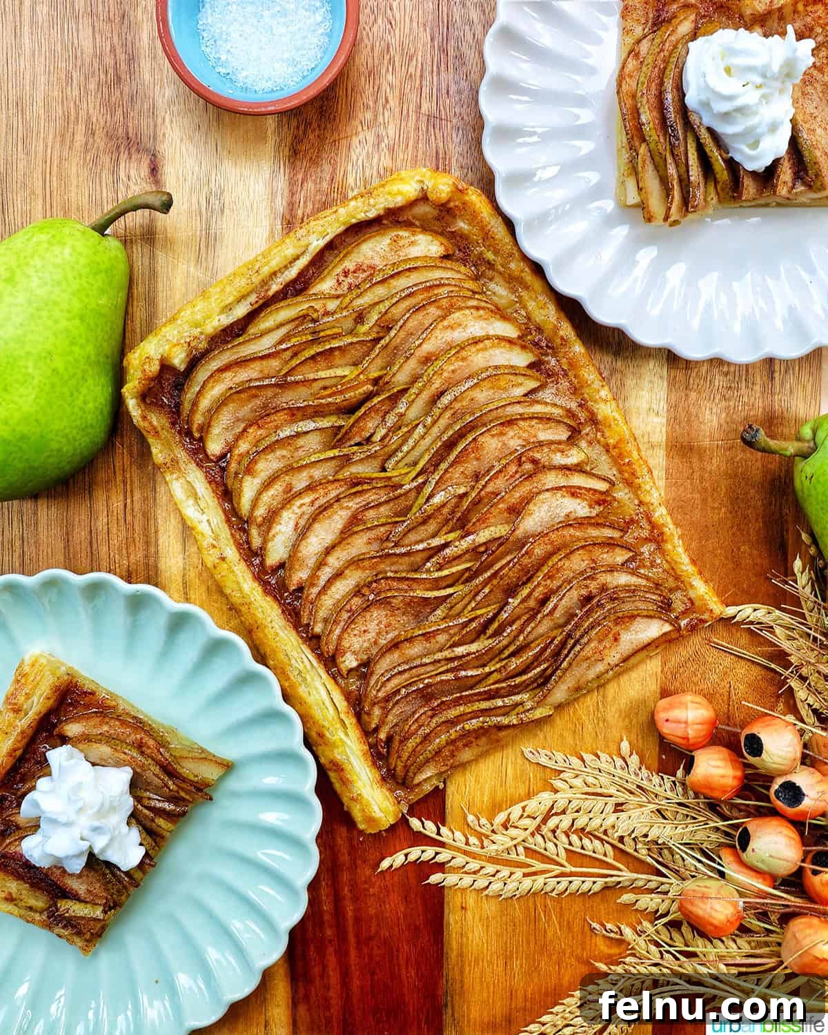 Overhead view of a beautifully arranged Ginger and Pear Tart with Puff Pastry, alongside plates of individual slices.