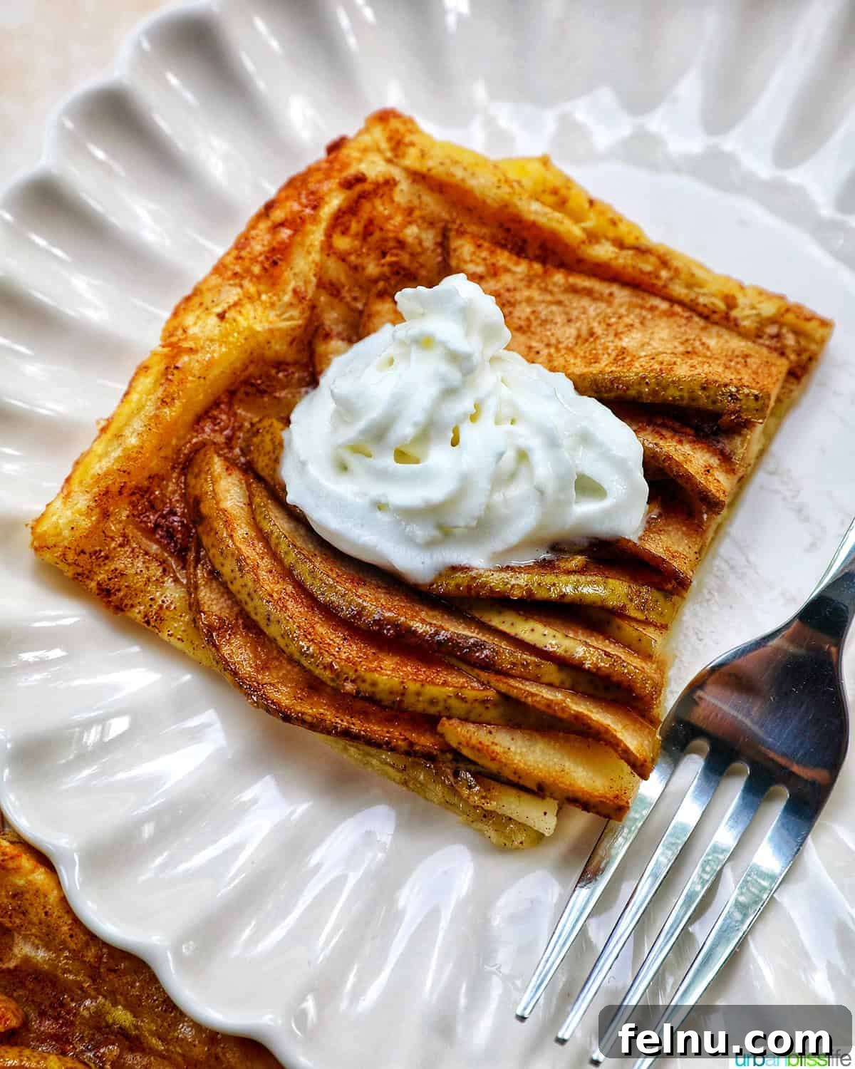 A slice of Ginger and Pear Tart with Puff Pastry on a plate, ready to be enjoyed.