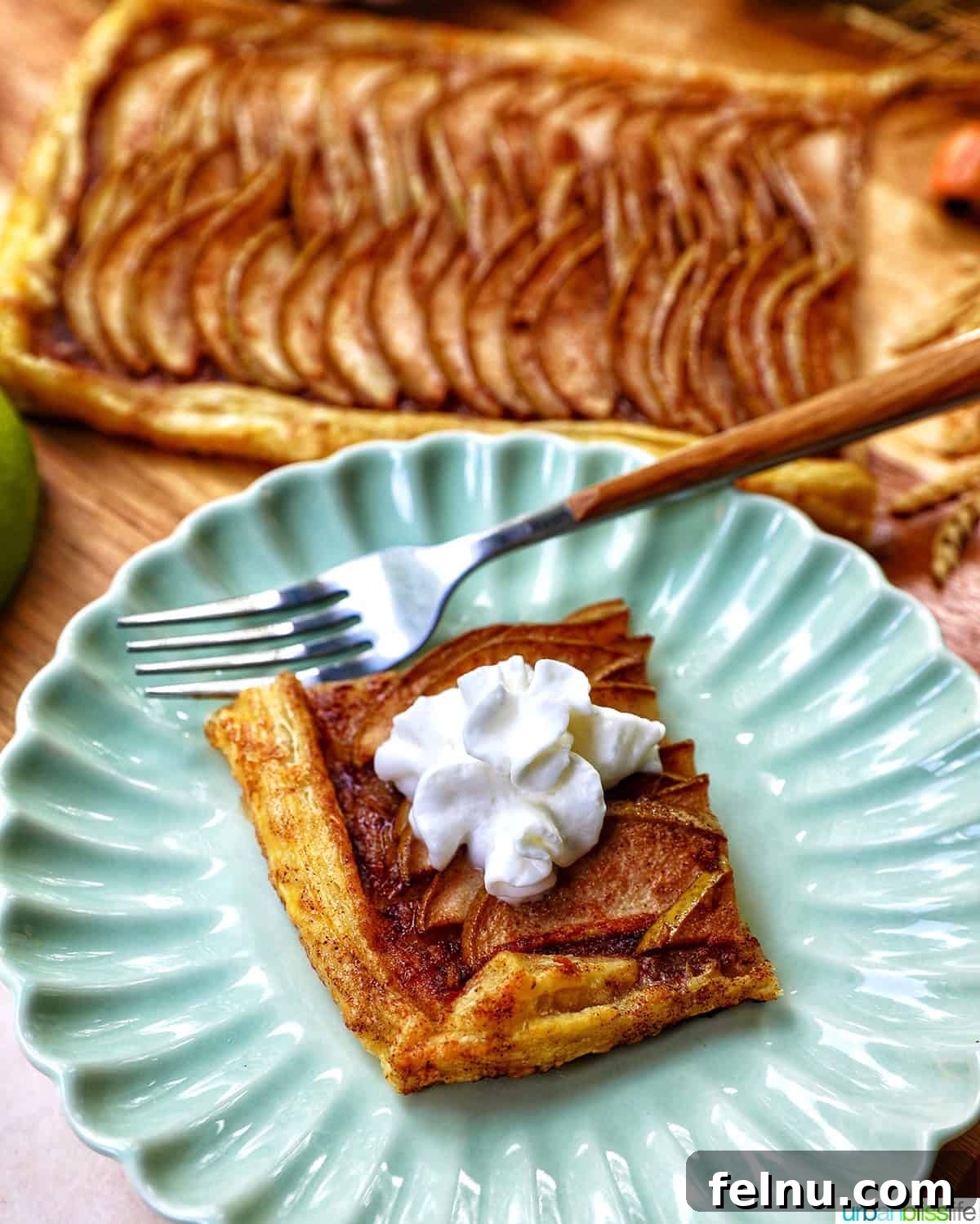 A slice of Ginger and Pear Tart with Puff Pastry on a plate, with a fork, ready to be eaten.