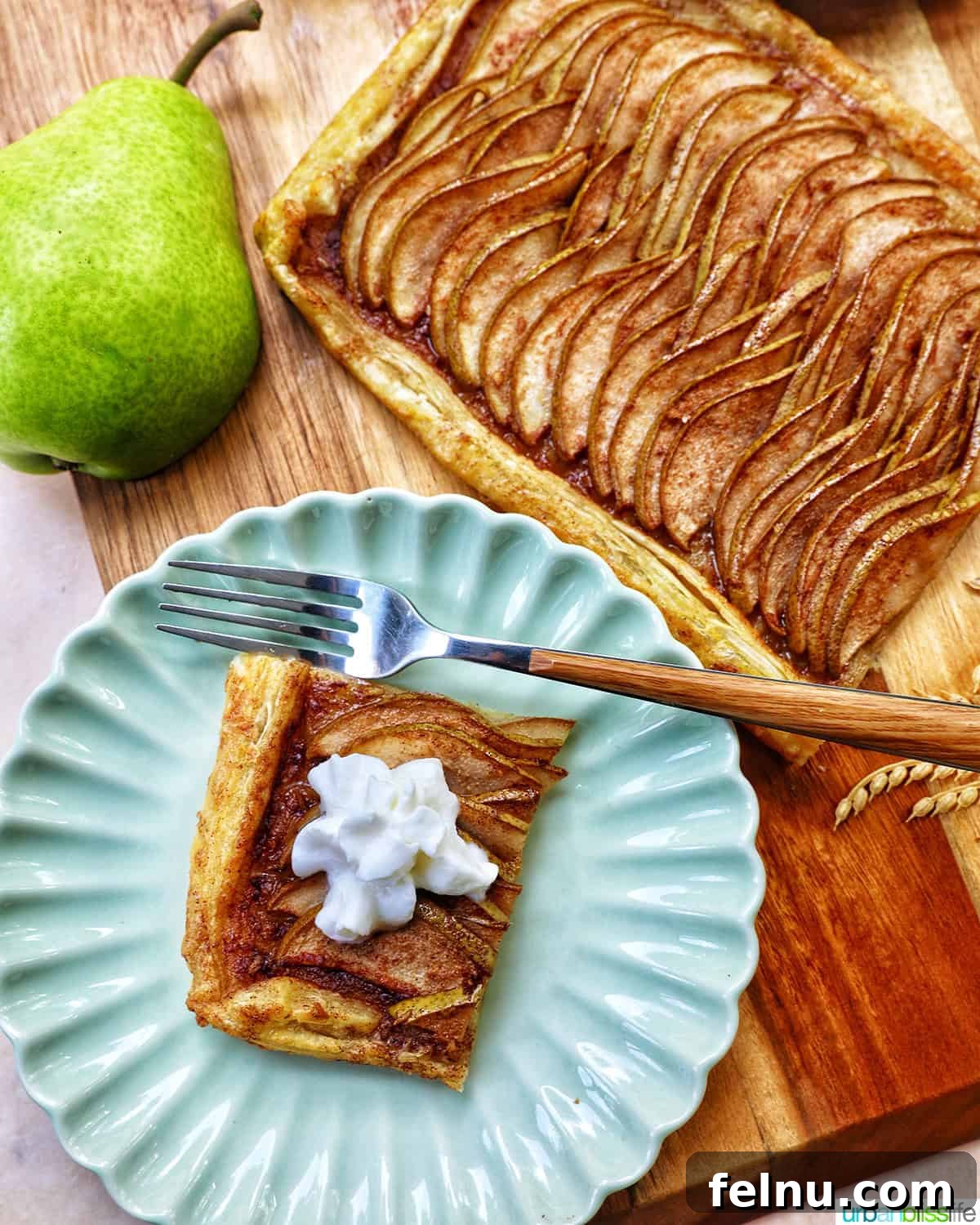 A slice of Ginger and Pear Tart with Puff Pastry, with a pear in the background, showcasing the simplicity and elegance of the dessert.