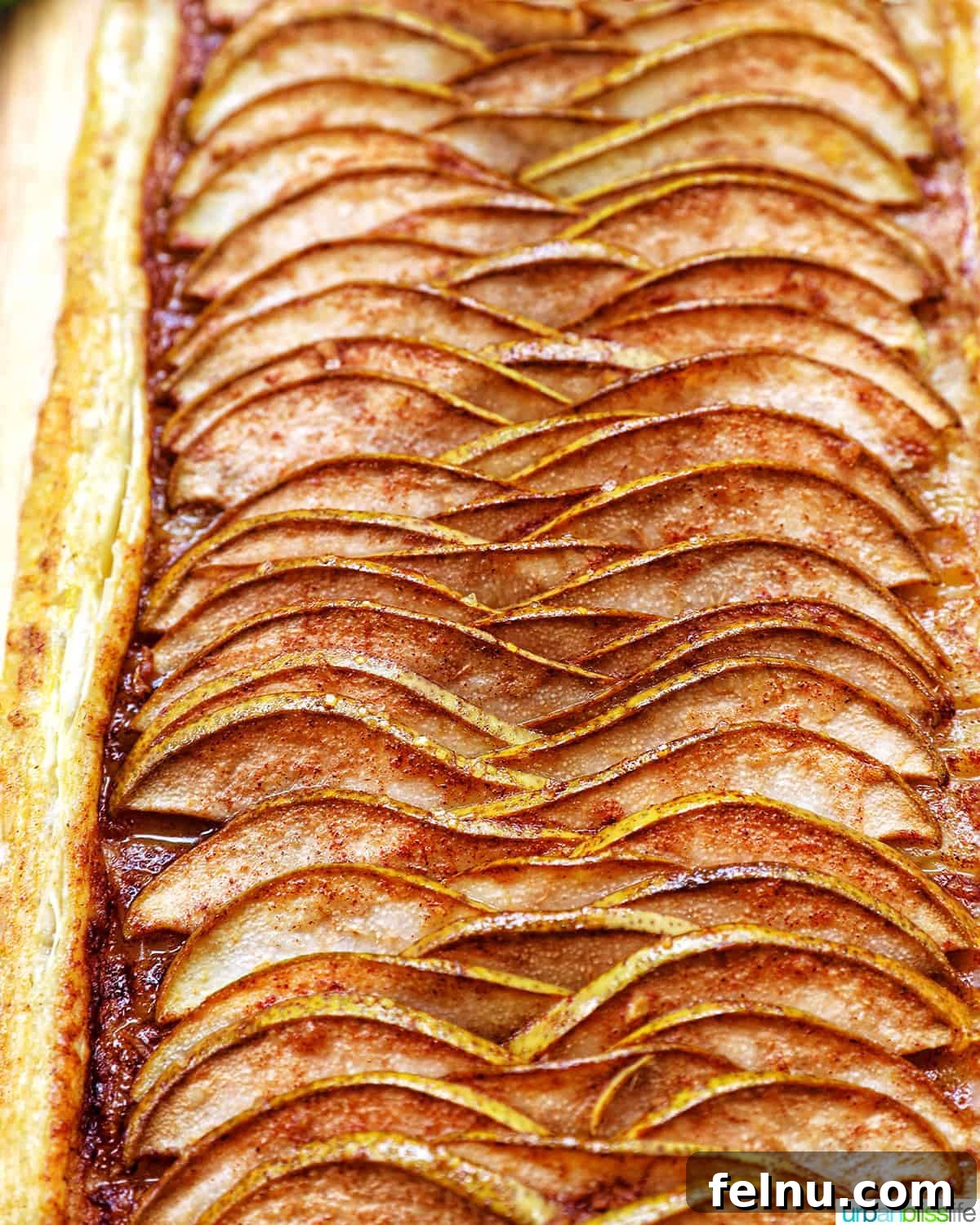 A close-up shot of a Ginger and Pear Tart with Puff Pastry, showcasing the golden-brown crust and caramelized pears.