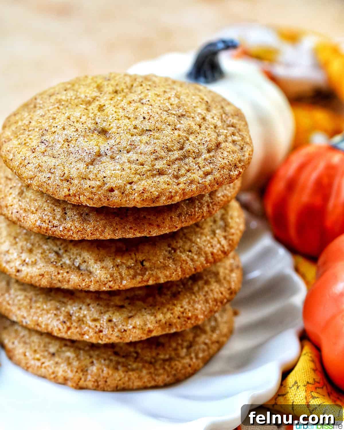 stack of pumpkin spice cookies with pumpkin decorations and cinnamon sticks.