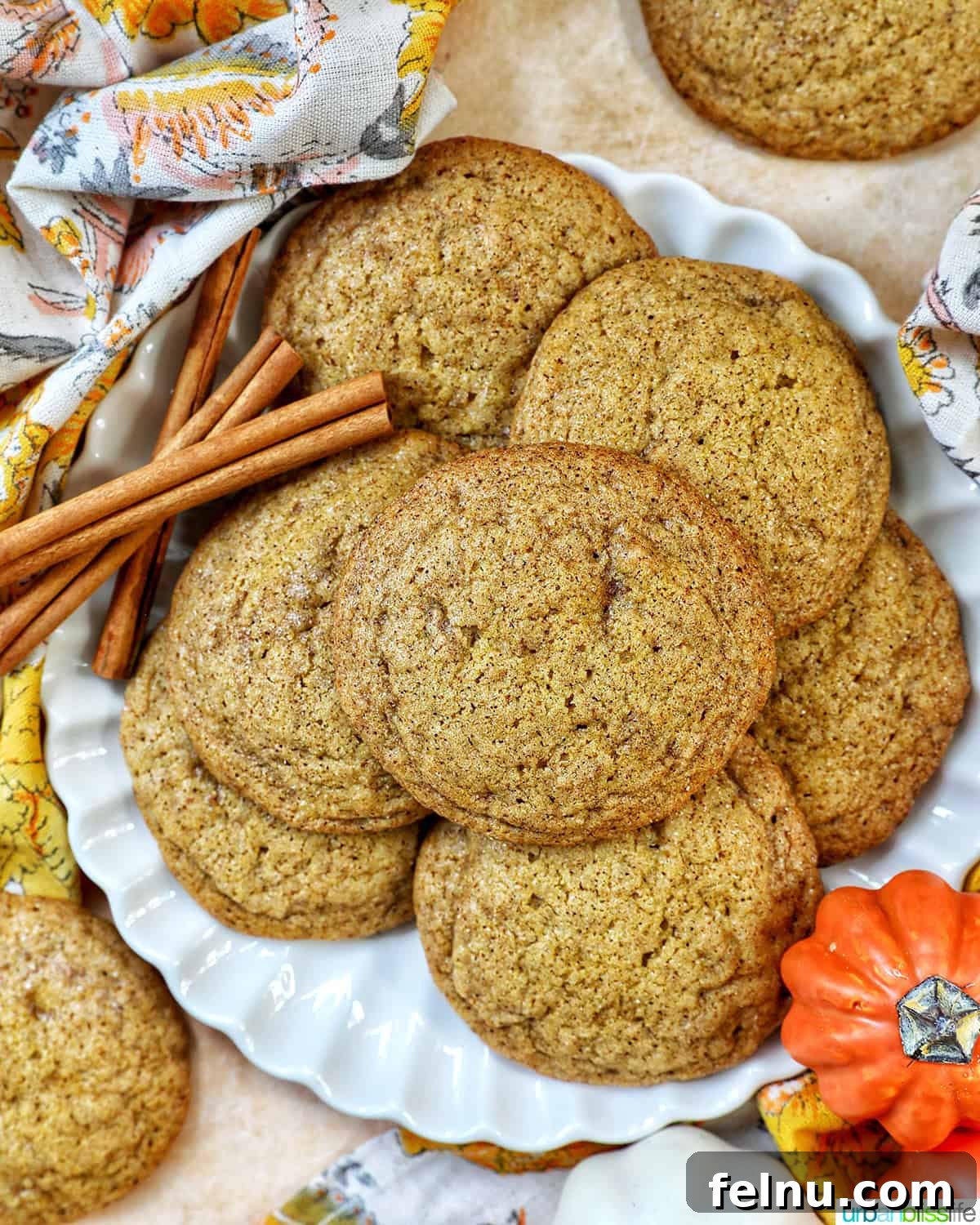 plate full of pumpkin spice cookies with pumpkin decorations and cinnamon sticks.