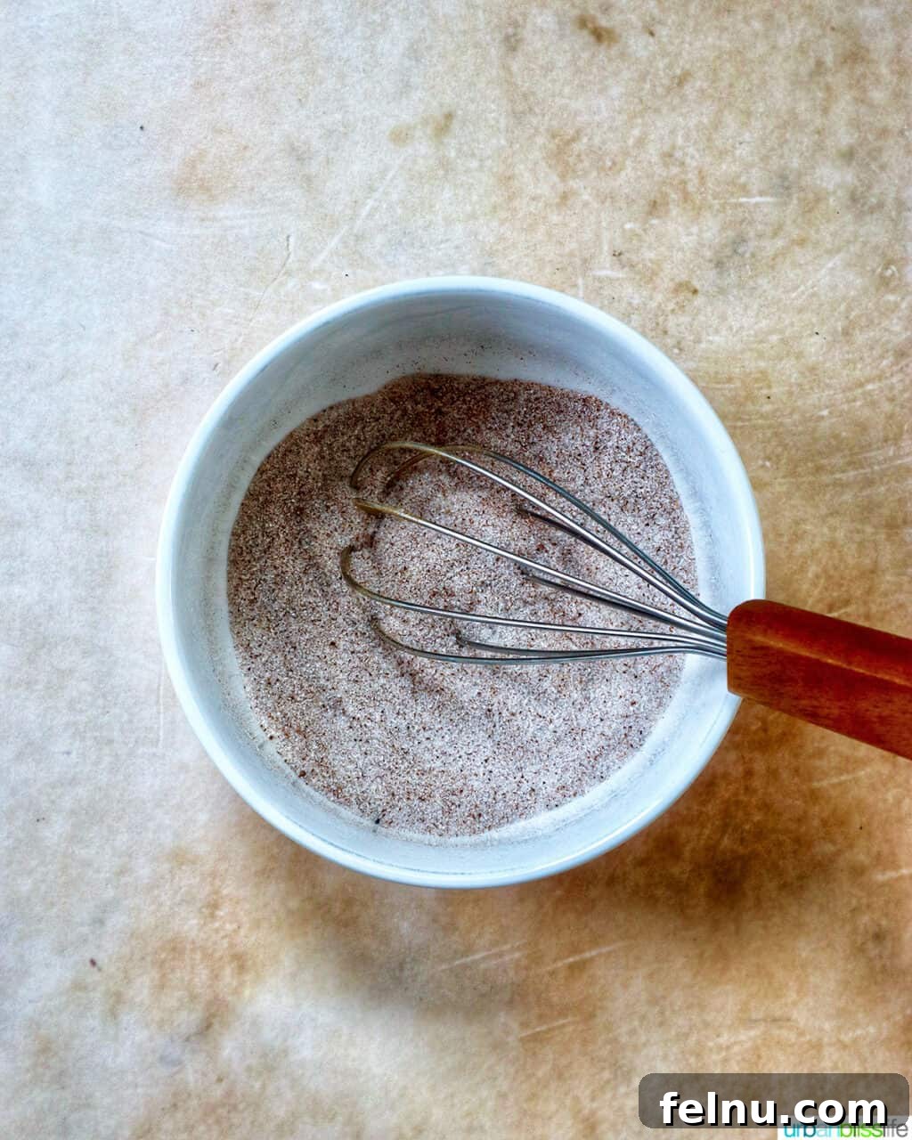 whisk with cinnamon sugar in a white bowl.