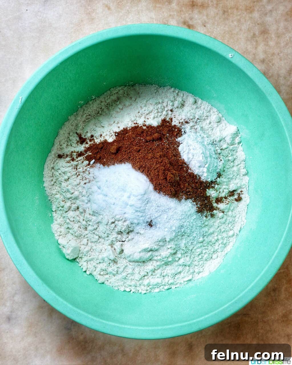 dry ingredients to make pumpkin spice cookies in a green bowl.