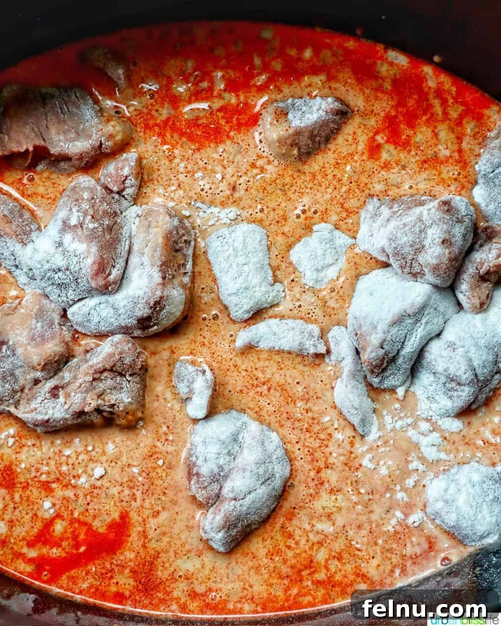 Slow Cooker Massaman Beef Curry 11 Adding the flour-coated beef to the slow cooker, layering it over the potatoes, onions, and curry sauce for the slow cooker beef massaman curry recipe.