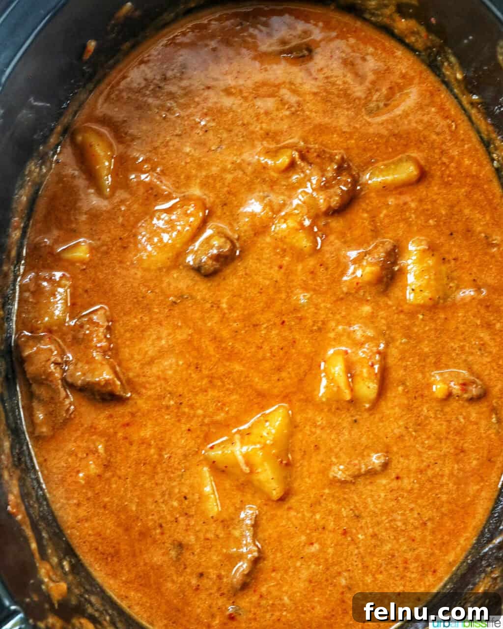 Slow Cooker Massaman Beef Curry 12 Overhead view of slow cooker beef massaman curry cooking in a crockpot slow cooker, showcasing the rich colors and simmering sauce.