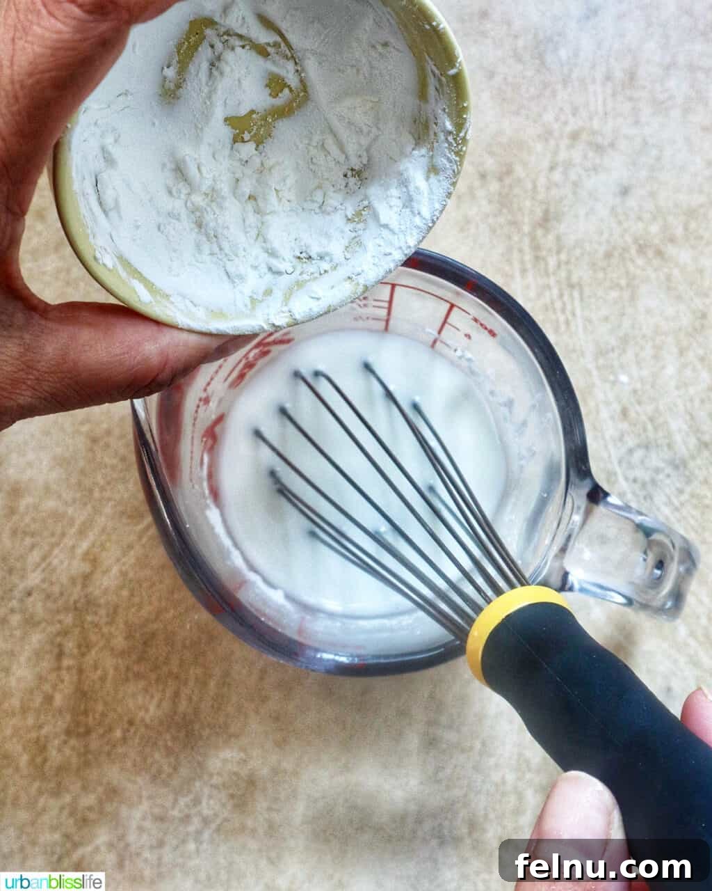 Smoky Sausage Pumpkin Bisque 13 A whisk smoothly blending cornstarch into a cup of cold water, creating a perfect cornstarch slurry for thickening the soup.