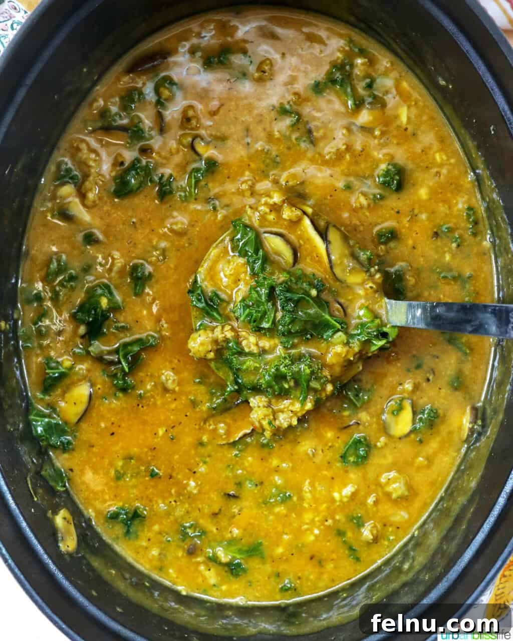 Smoky Sausage Pumpkin Bisque 14 A ladle filled with rich pumpkin soup and hearty sausage, poised above a Dutch oven, ready to be served.