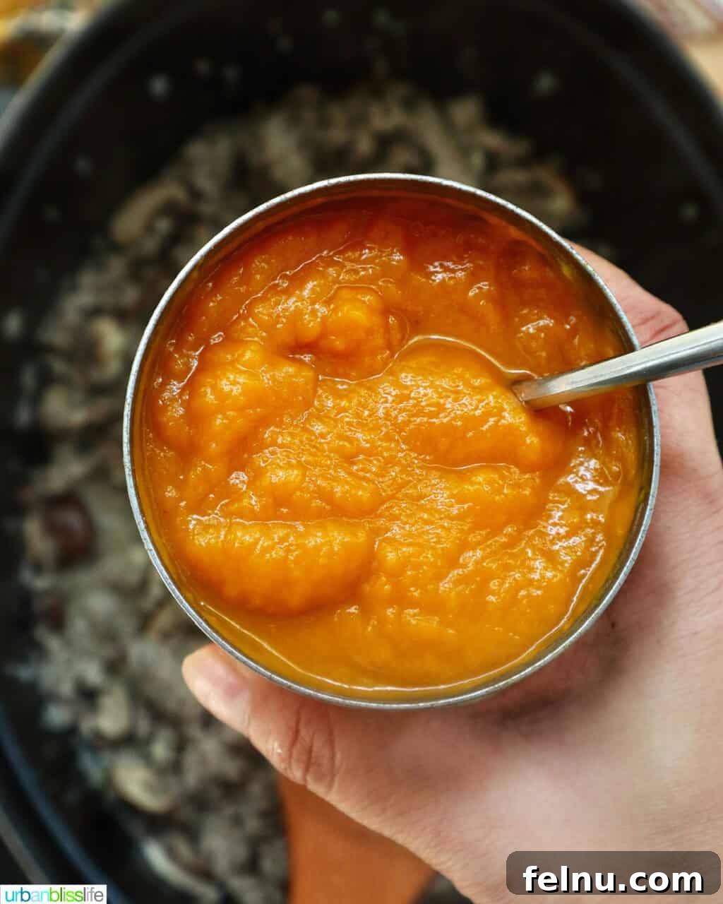 Smoky Sausage Pumpkin Bisque 9 A can of rich pumpkin puree being poured into a Dutch oven, joining the simmering soup base to create its signature creamy texture.
