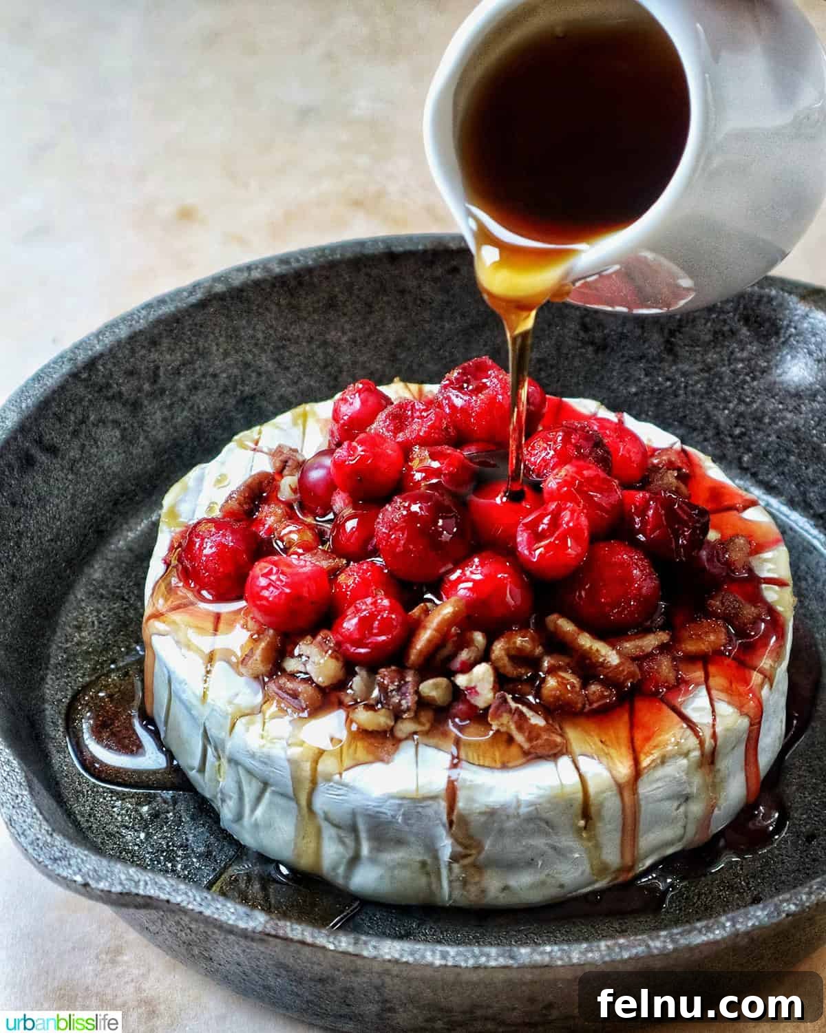 Cranberry and Pecan Crusted Brie 11 Drizzling honey over Cranberry Pecan Baked Brie in a skillet.