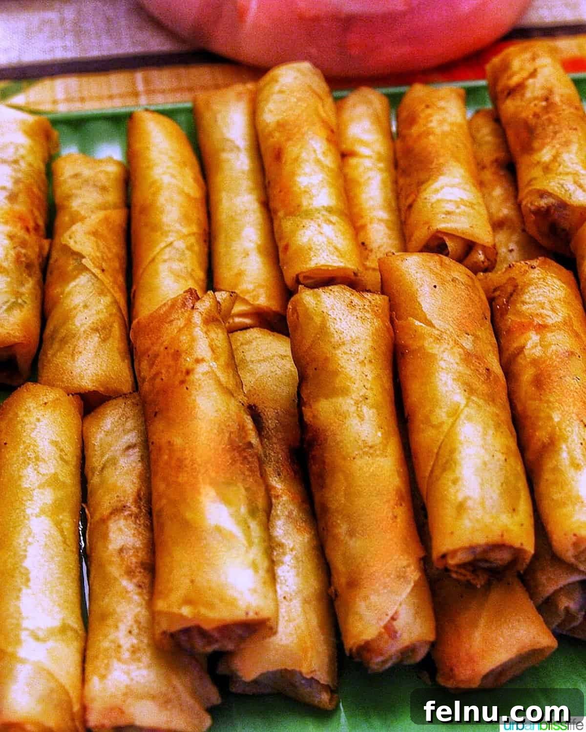 Tray of several stacked crispy Filipino lumpia, egg rolls, ready to be served.