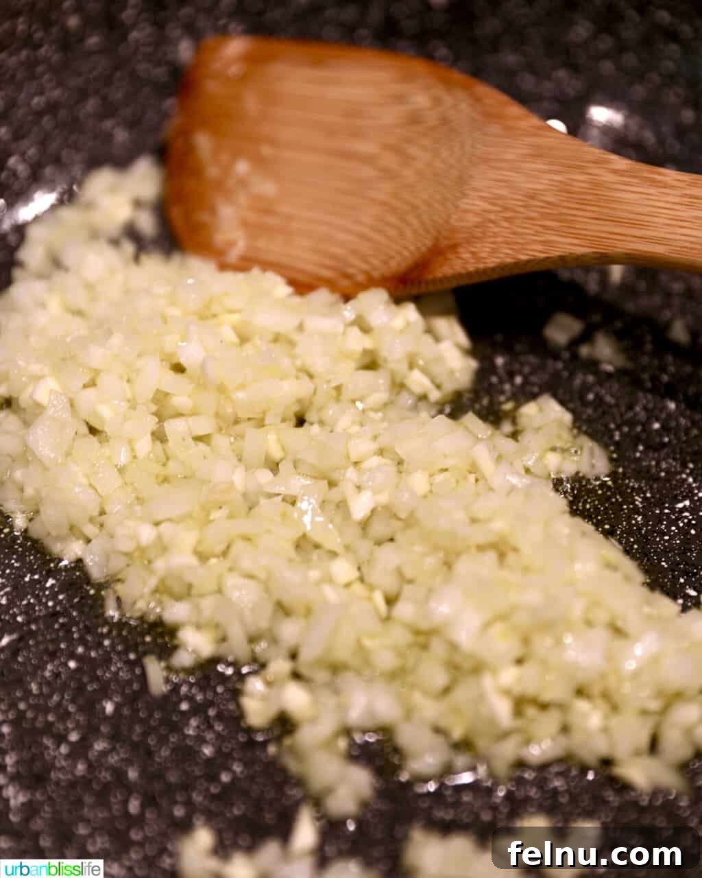 Sautéing minced garlic and diced onions in a large pan, releasing their aromatic flavors for the lumpia filling.